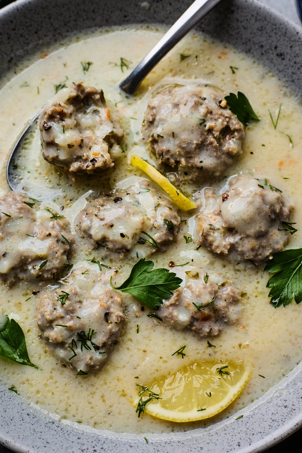 A close up Youvarlakia Avgolemono with meatballs and one cut open